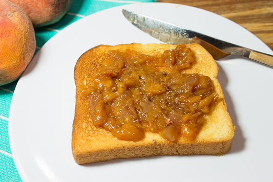 salted honey peach jam spread on a slice placed on a plate with a knife