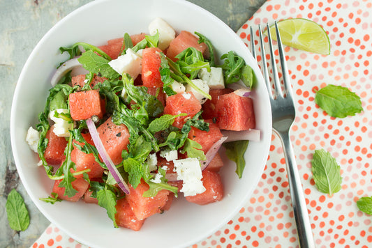 salad bowl with spoon, leaves, and table mat in the background