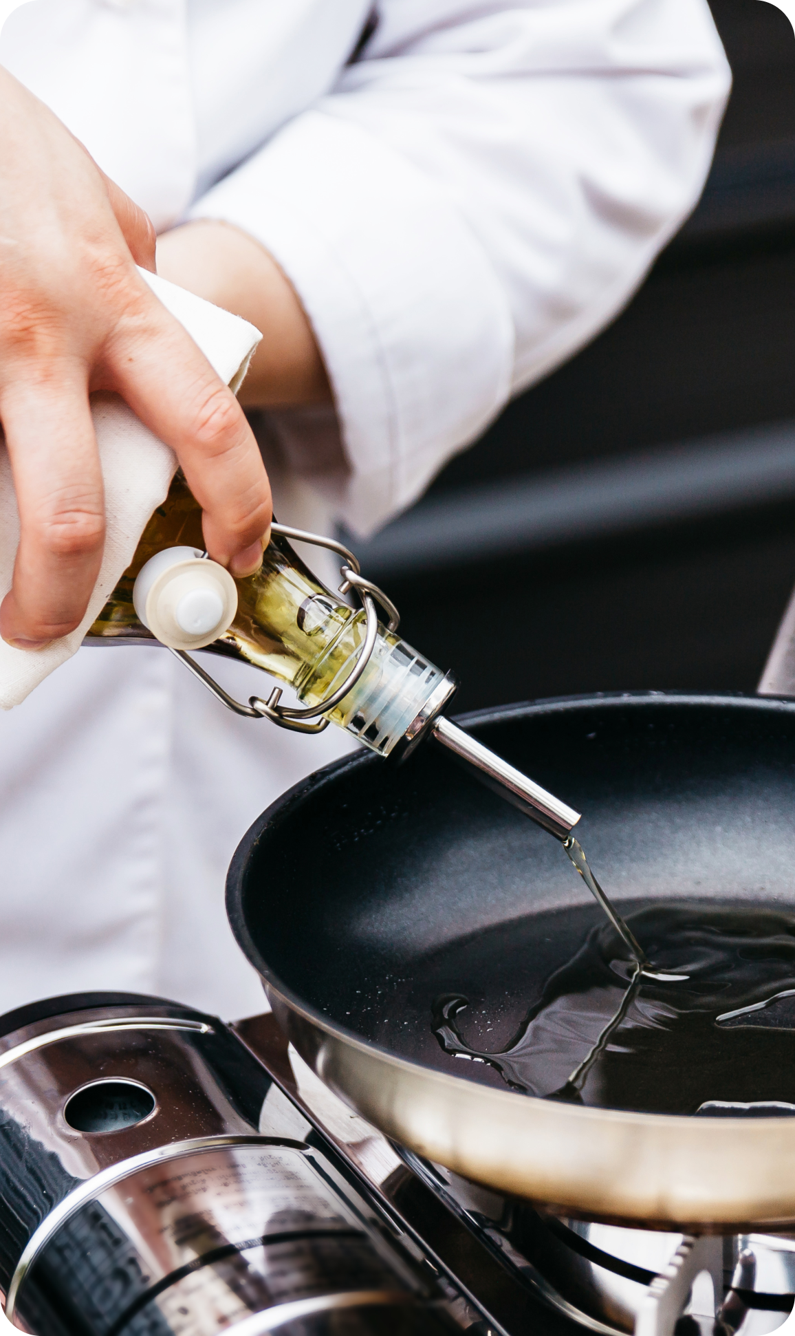 a person pouring oil through pourer spout in a pan