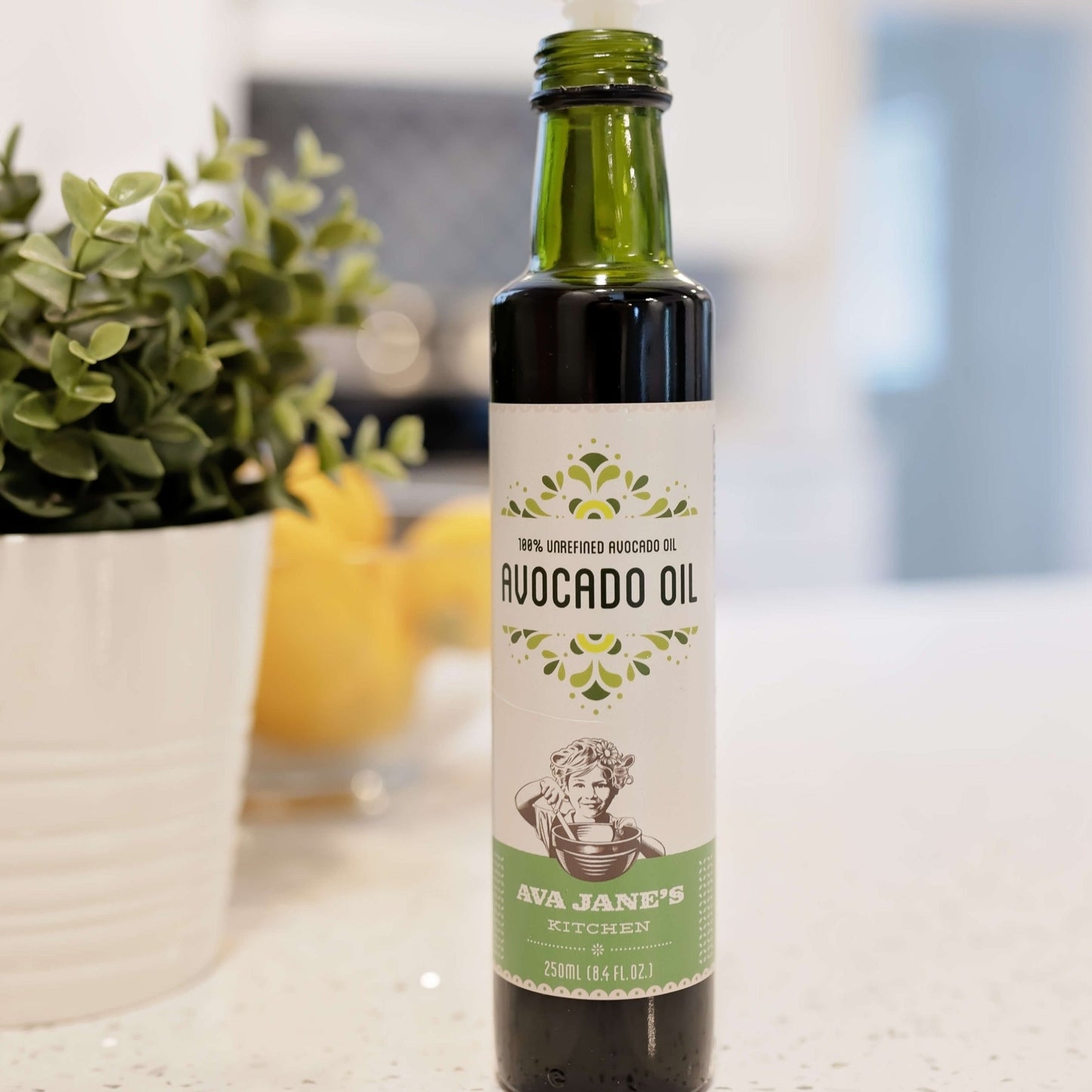 Bottle of Ava Jane's Kitchen's Avocado oil on the kitchen counter sitting in front of a potted plant