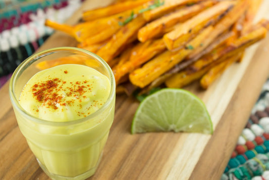 avocado oil mayonnaise in a glass, french fires, and lemon placed on wooden tray