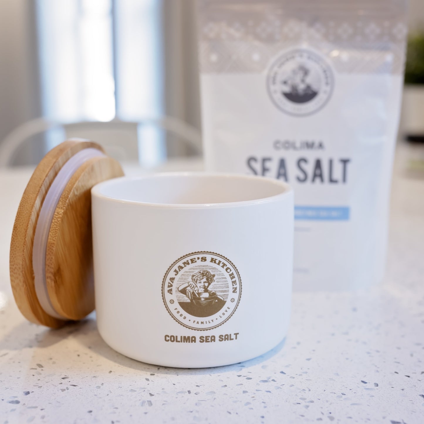 Ava Jane Kitchen's porcelain salt cellar sitting opened on the kitchen counter with a bag of colima sea salt in the background