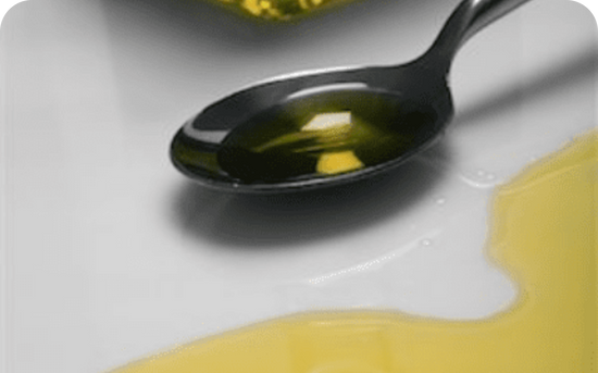 spoon placed on a surface containing oil, while oil is spilled on one side of the spoon
